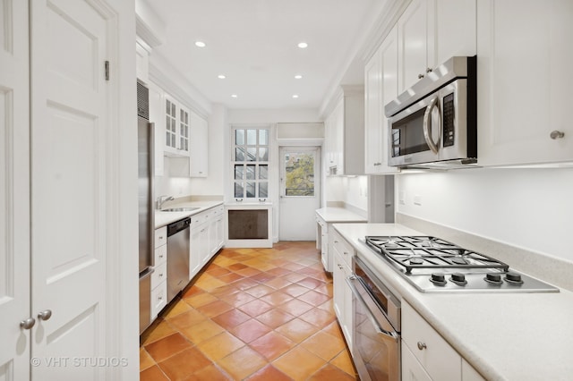 kitchen with white cabinets, appliances with stainless steel finishes, light tile patterned flooring, and sink