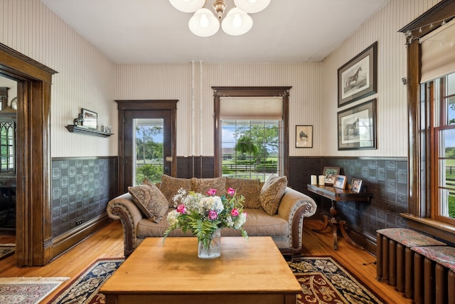 living room with wood-type flooring, radiator, and a notable chandelier