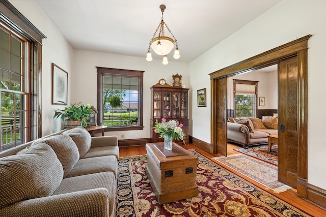 living room with an inviting chandelier, wood-type flooring, and a healthy amount of sunlight