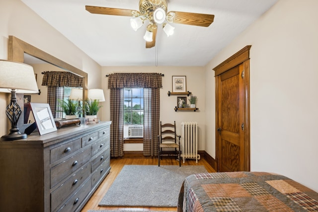 bedroom featuring radiator heating unit, ceiling fan, and light wood-type flooring