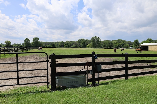 view of gate with a lawn and a rural view