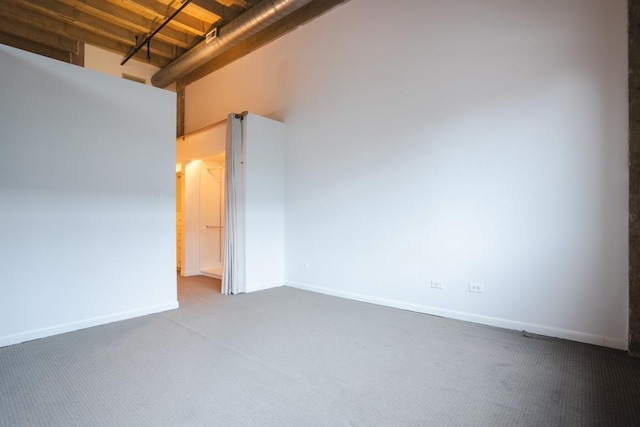 carpeted spare room featuring a towering ceiling