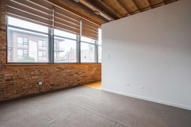 empty room featuring carpet flooring and brick wall