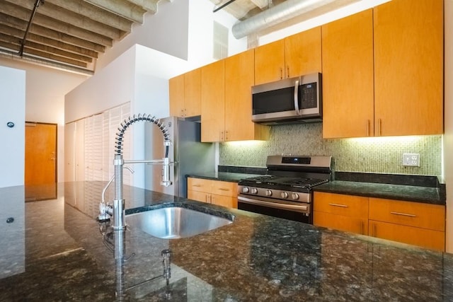 kitchen featuring backsplash, sink, dark stone counters, and appliances with stainless steel finishes