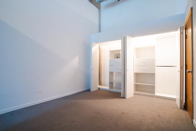 unfurnished bedroom featuring carpet flooring, high vaulted ceiling, and a closet