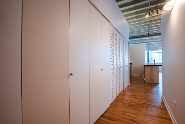 hall with light hardwood / wood-style floors, sink, and track lighting