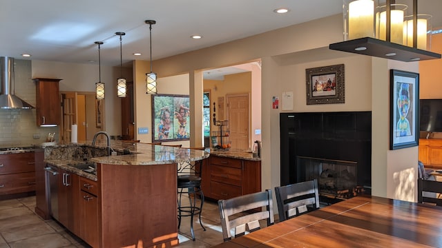 kitchen featuring a breakfast bar area, pendant lighting, light tile patterned floors, a kitchen island, and wall chimney exhaust hood