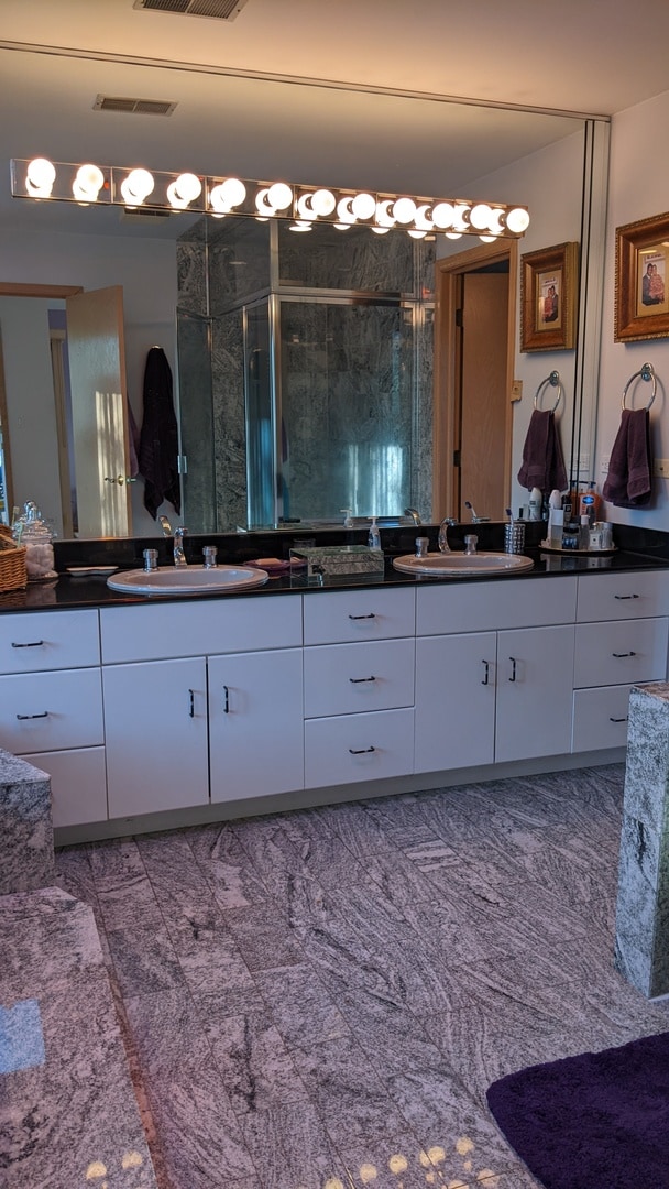 bathroom with walk in shower and dual bowl vanity