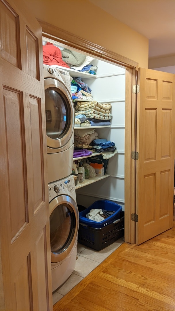 clothes washing area with light tile patterned floors and stacked washer / drying machine