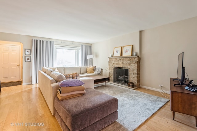 living room featuring a stone fireplace and light hardwood / wood-style floors