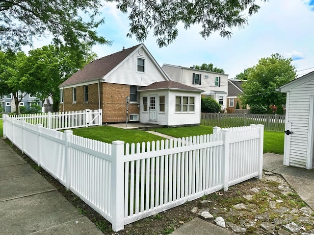 view of front of home with brick siding, a front lawn, and a fenced backyard