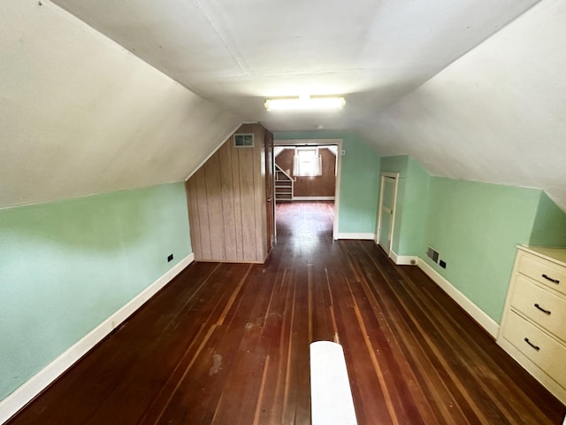 additional living space with dark wood-style floors, visible vents, vaulted ceiling, and baseboards