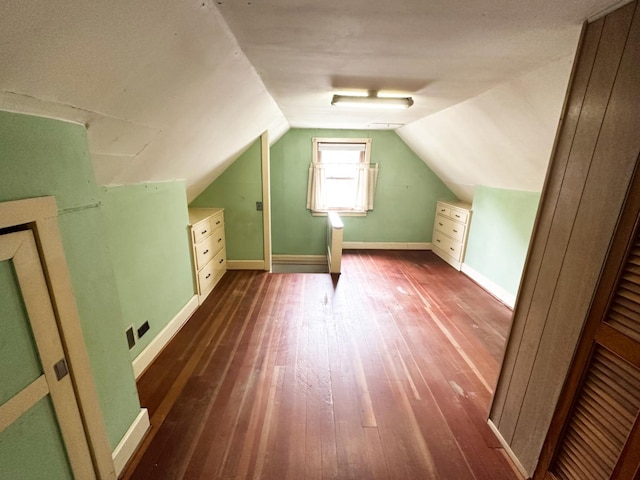 additional living space featuring lofted ceiling, baseboards, and dark wood finished floors