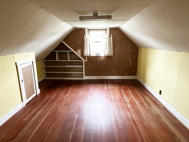 additional living space with built in features, baseboards, vaulted ceiling, and hardwood / wood-style floors