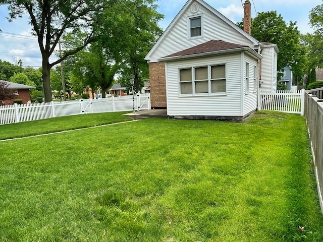 exterior space with a fenced backyard, a lawn, and a chimney