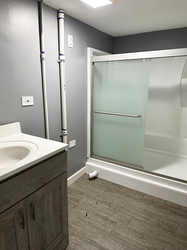 full bath with vanity, baseboards, wood finished floors, and a shower with shower door