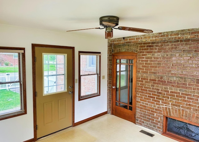 doorway to outside with baseboards, visible vents, brick wall, light floors, and a brick fireplace