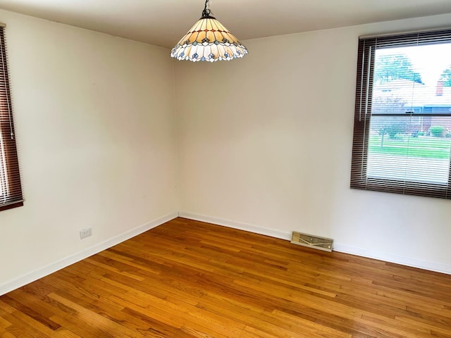 spare room with visible vents, baseboards, and wood finished floors