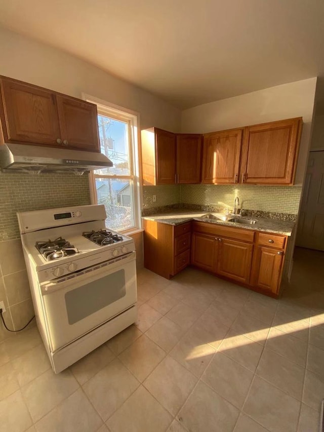 kitchen with sink, white range with gas stovetop, light tile patterned floors, and decorative backsplash