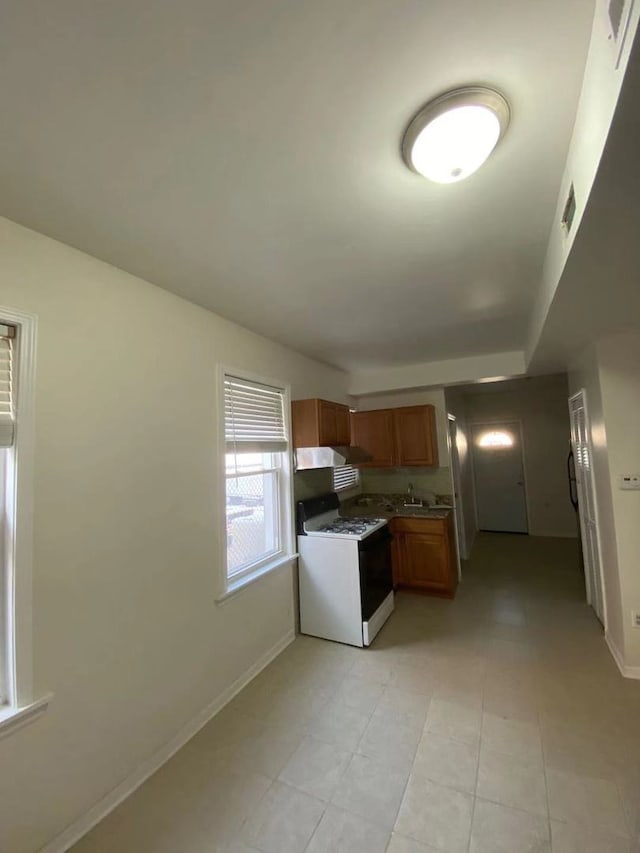 kitchen featuring sink, light tile patterned floors, and white range with gas stovetop