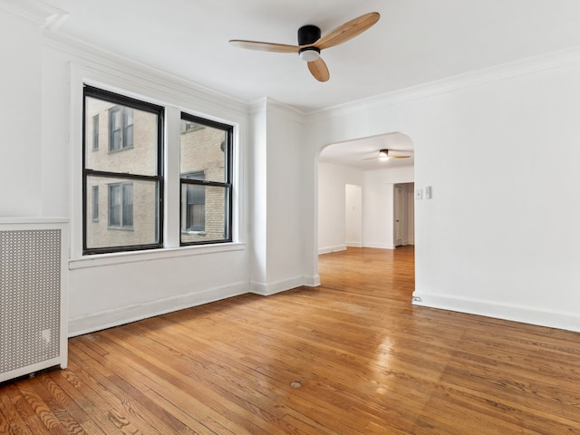 empty room with ornamental molding, radiator heating unit, light hardwood / wood-style flooring, and ceiling fan