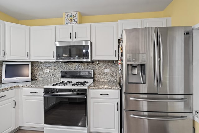 kitchen with white cabinets, light stone countertops, backsplash, and appliances with stainless steel finishes