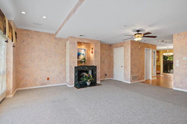 unfurnished living room featuring a fireplace, light carpet, ceiling fan with notable chandelier, and crown molding