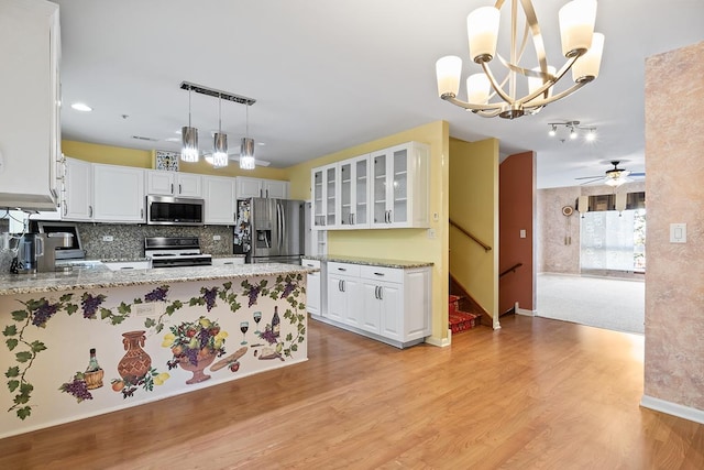 kitchen featuring kitchen peninsula, appliances with stainless steel finishes, tasteful backsplash, decorative light fixtures, and white cabinetry