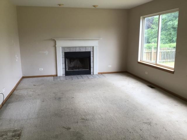 unfurnished living room with a tiled fireplace and light colored carpet