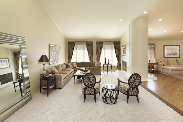 living room featuring vaulted ceiling, ornamental molding, and light wood-type flooring