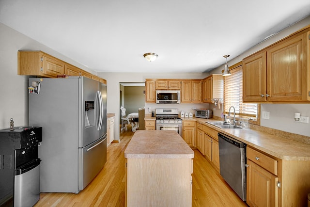 kitchen with decorative light fixtures, sink, a center island, stainless steel appliances, and light hardwood / wood-style flooring