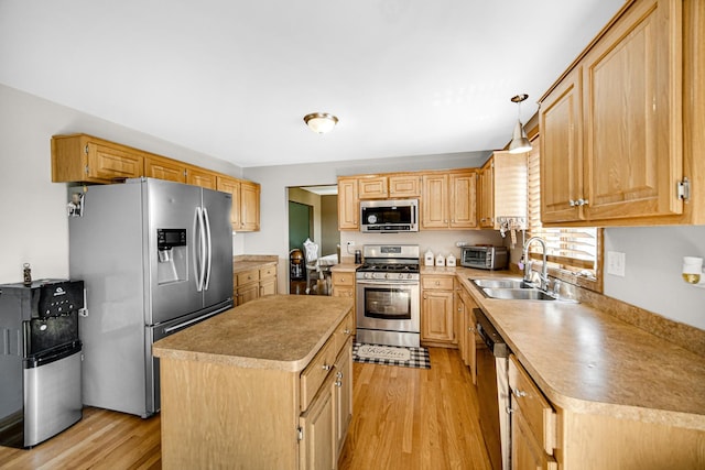 kitchen with sink, hanging light fixtures, light wood-type flooring, a kitchen island, and stainless steel appliances