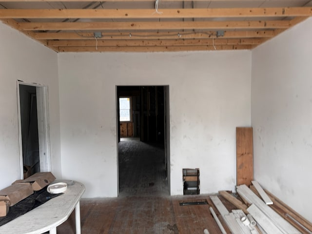 interior space with beam ceiling, dark wood-type flooring, and a towering ceiling