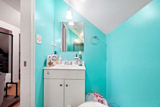 bathroom featuring wood-type flooring, toilet, vanity, and lofted ceiling