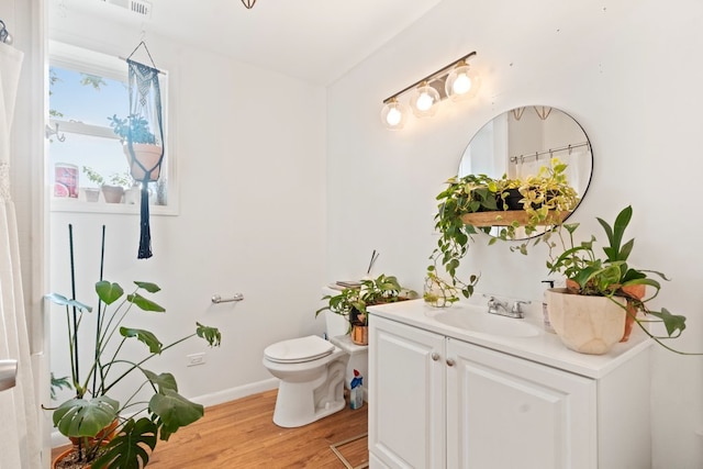 bathroom with toilet, hardwood / wood-style floors, and vanity