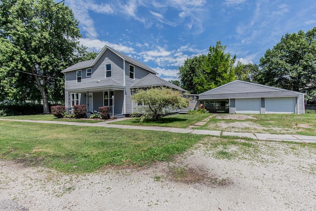 view of front of house with a front yard, an outbuilding, a garage, and covered porch