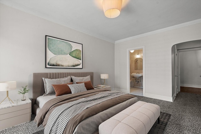 bedroom with ensuite bath, dark carpet, and ornamental molding