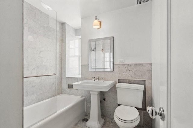 bathroom featuring tile walls, toilet, and a bath