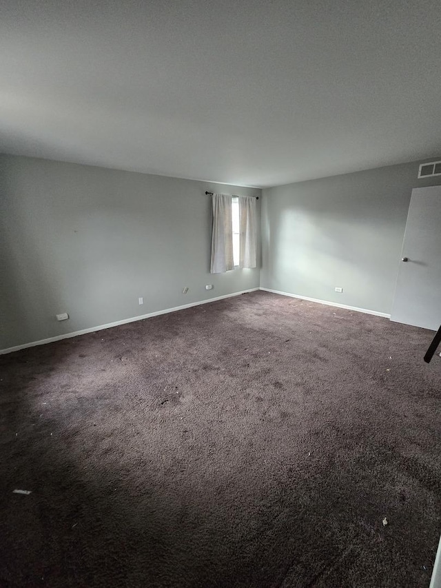 unfurnished room featuring dark colored carpet