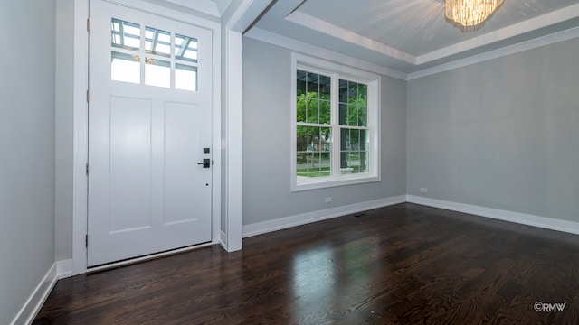 foyer entrance with dark wood-type flooring, an inviting chandelier, and a raised ceiling