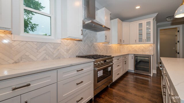 kitchen featuring dark wood-type flooring, decorative light fixtures, high end stove, wall chimney range hood, and beverage cooler