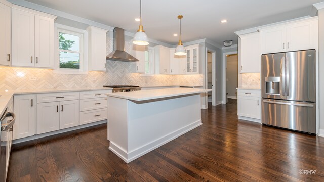 kitchen featuring stainless steel appliances, dark hardwood / wood-style flooring, white cabinetry, wall chimney range hood, and a kitchen island