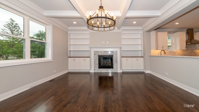 unfurnished living room featuring dark wood-type flooring, a chandelier, a high end fireplace, and beam ceiling