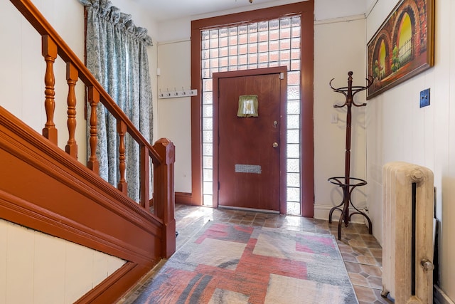 entryway with stone finish flooring, a healthy amount of sunlight, stairway, and radiator heating unit