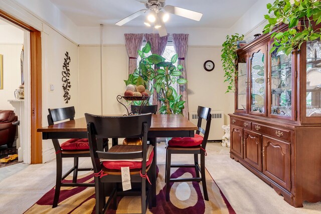 carpeted dining room with radiator heating unit and ceiling fan