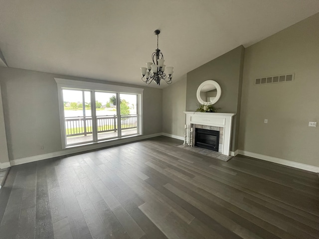 unfurnished living room featuring lofted ceiling, dark wood-type flooring, a notable chandelier, and a tile fireplace