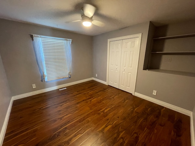 unfurnished bedroom with a textured ceiling, dark hardwood / wood-style floors, a closet, and ceiling fan