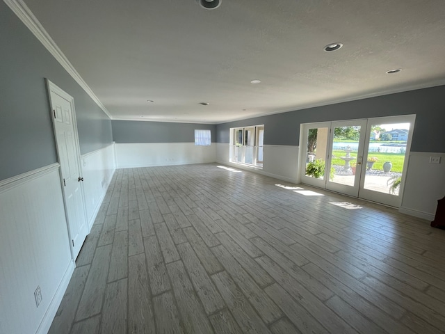 empty room featuring french doors, light hardwood / wood-style floors, and crown molding