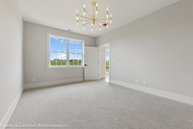 carpeted empty room featuring an inviting chandelier