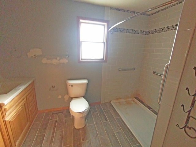 bathroom featuring toilet, vanity, and a tile shower